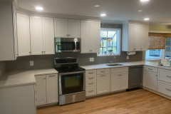 Remodeled white kitchen with quartz counters and tile backsplash