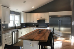 Open kitchen with butcher-block island, dark backsplash, and stainless fridge