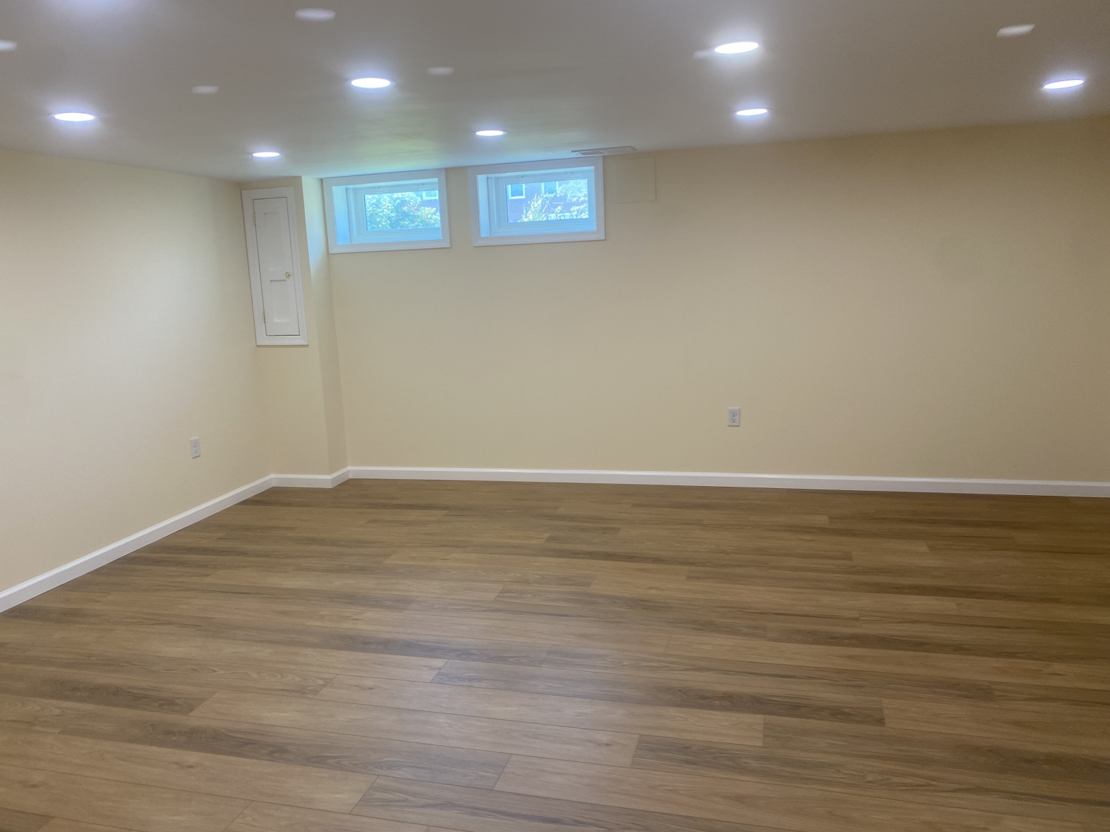 Finished basement great room with egress windows, wood-look flooring, and recessed lights