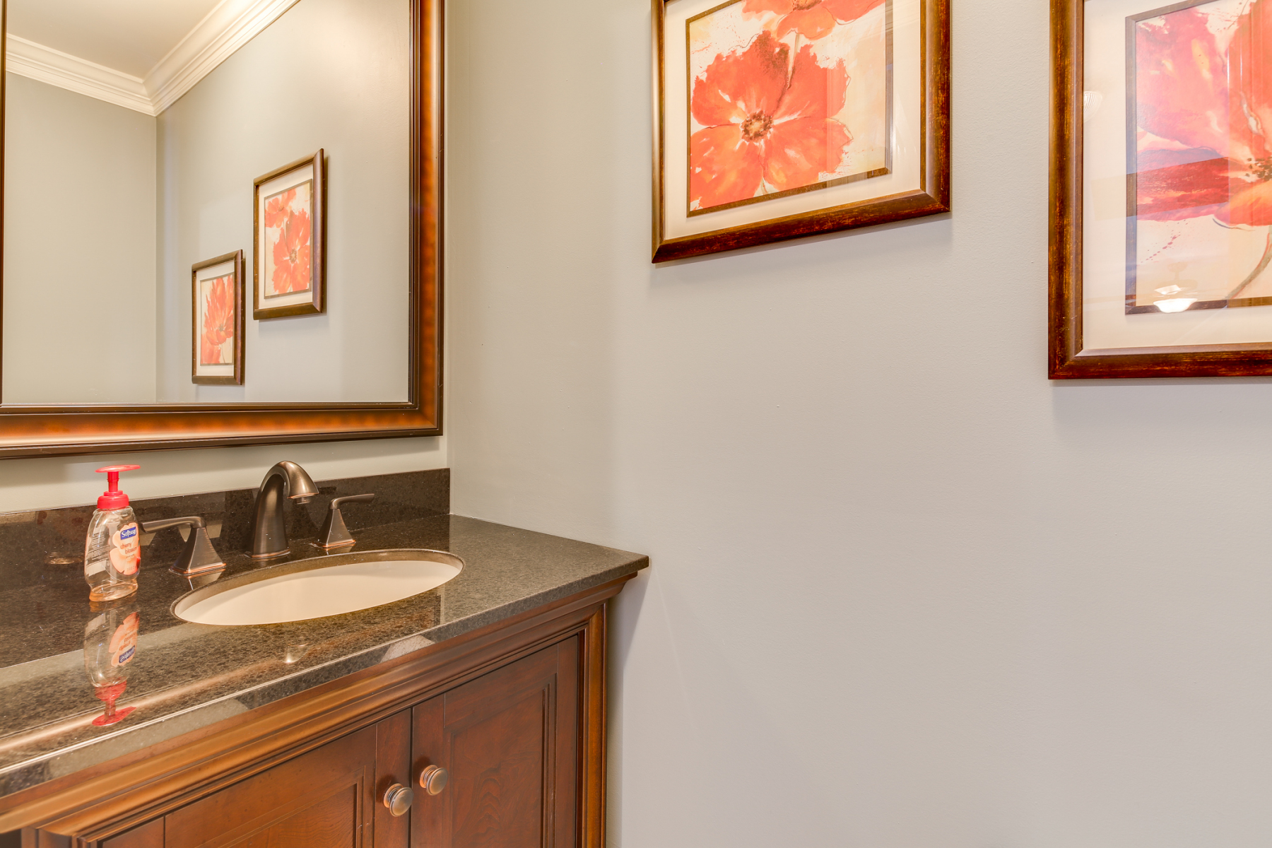 Powder room with granite-top wood vanity, framed mirror, and fresh paint