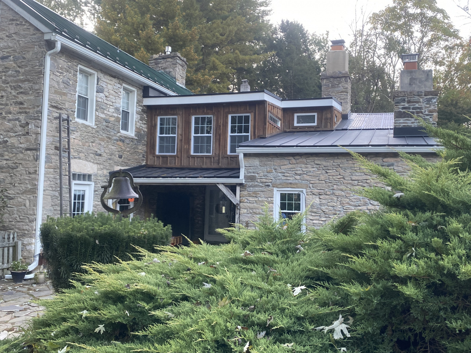 Completed second-floor addition with board-and-batten siding, metal roof, and new dormer windows