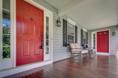 Covered front porch with red door and hardwood flooring