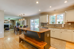 Open kitchen with butcher-block island, bench seating, and tile backsplash