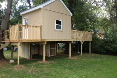Side view of two-story playhouse with elevated deck and lower storage