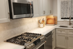 Kitchen corner with stainless microwave, gas range, and tile backsplash