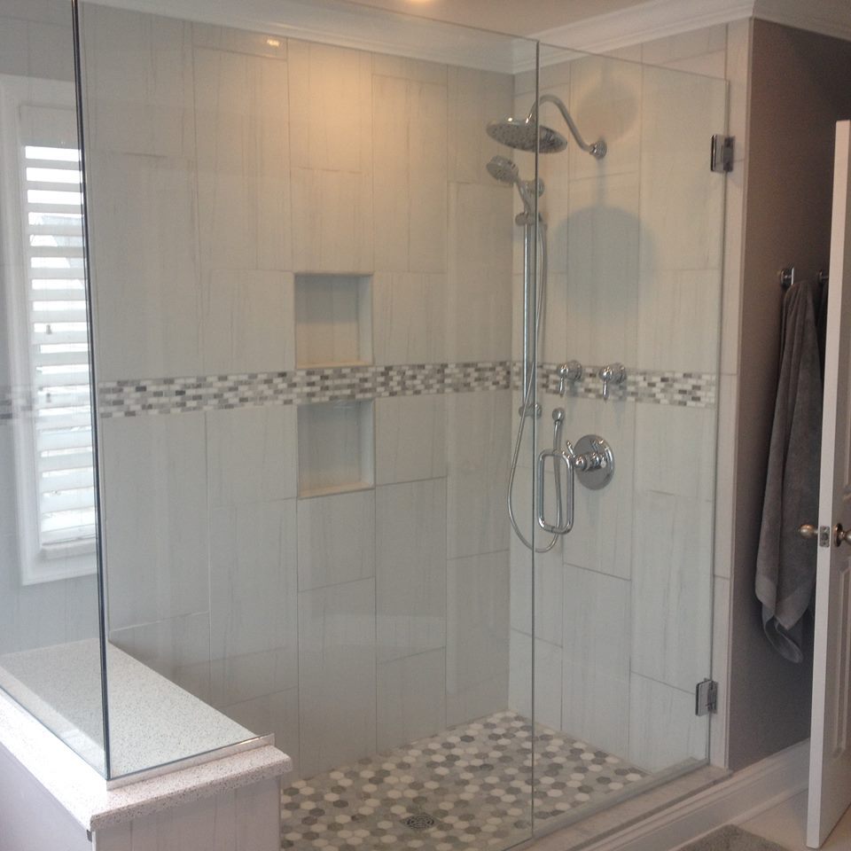 Frameless glass shower with marble tile, mosaic accent band, and hex floor