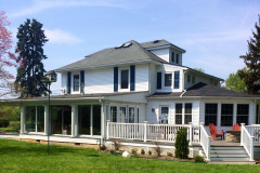 Wraparound covered porch with white railings on a two-story home