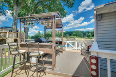 Deck pergola bar with stools and view of the yard