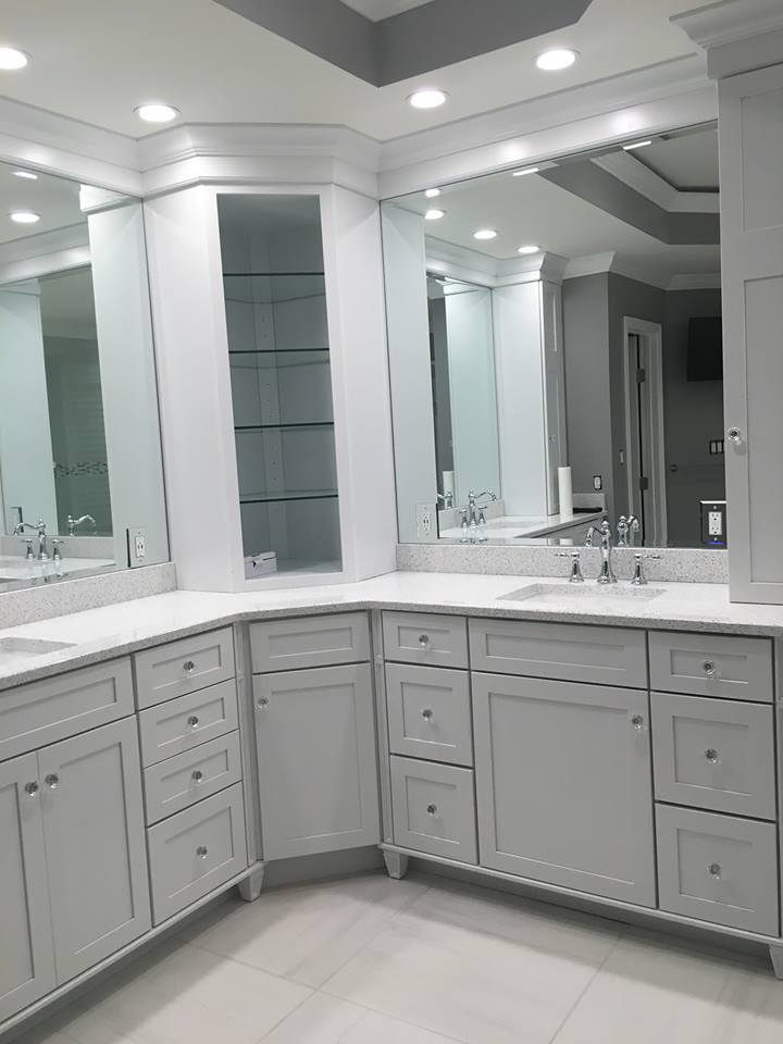 Remodeled master bath with custom corner vanity, quartz counters, and mirrored walls