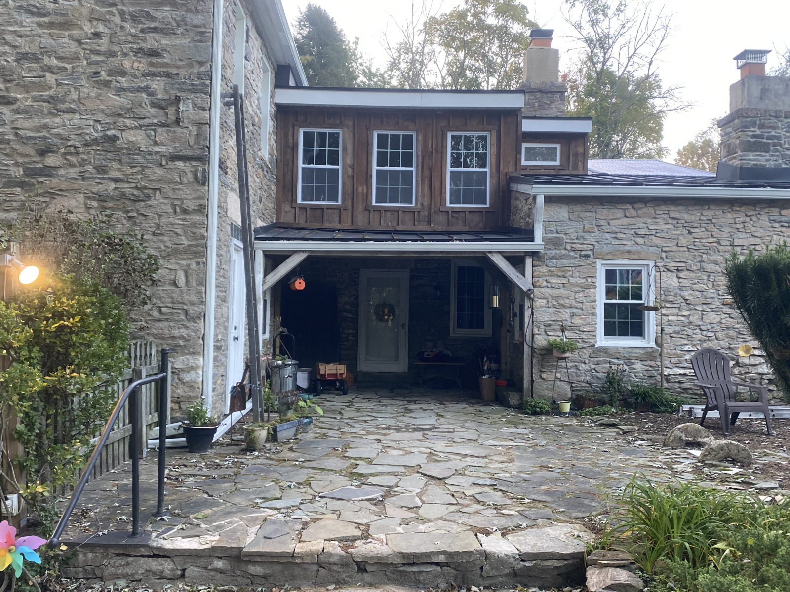 Rear view of completed second-floor addition with reclaimed wood siding above original stone walls