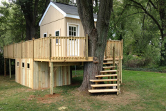 Two-story playhouse with elevated deck, stairs, and lower storage
