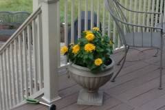 Composite deck detail with white posts and planter of yellow flowers